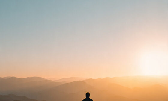 A peaceful person standing on a mountain at sunrise, symbolizing Stoic awareness, calm readiness, and tranquility in uncertain times.