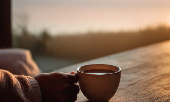 A serene morning moment showing a person enjoying a simple pleasure, sipping tea at sunrise, symbolizing peace, gratitude, and the beauty of simplicity.