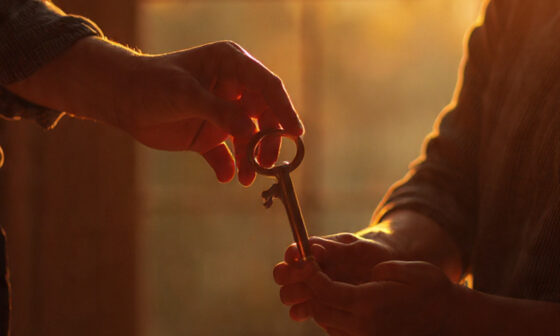 Hands holding a key above an open Bible, representing faithfulness, integrity, and the responsibility of being a trusted steward of God’s gifts.