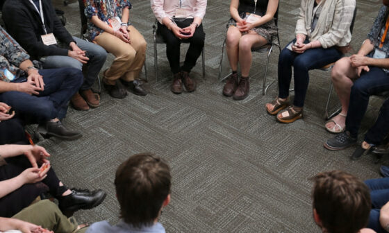 A group of people sitting in a circle for a dialogue-based learning session.