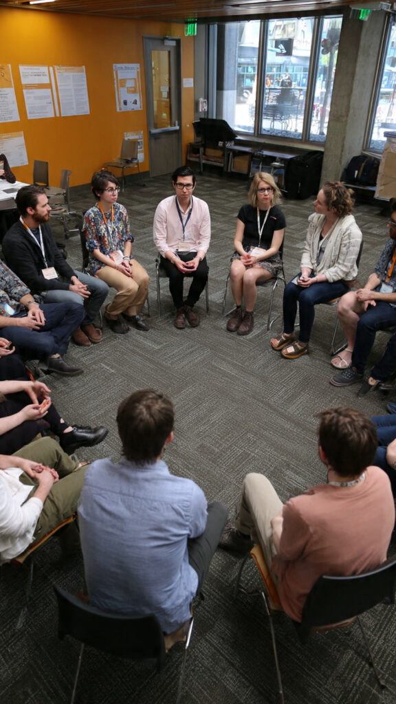 A group of people sitting in a circle for a dialogue-based learning session.