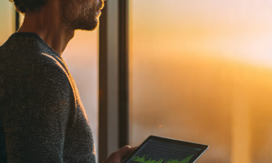 Professional man planning for financial freedom while looking at a growing wealth chart during sunrise.