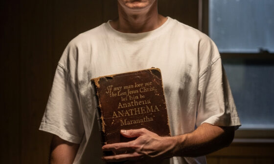 A person standing in darkness looking toward a bright light, representing the warning of Anathema Maranatha and the coming of the Lord