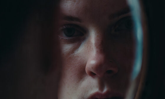 A person looking into a mirror with a serious, reflective expression.